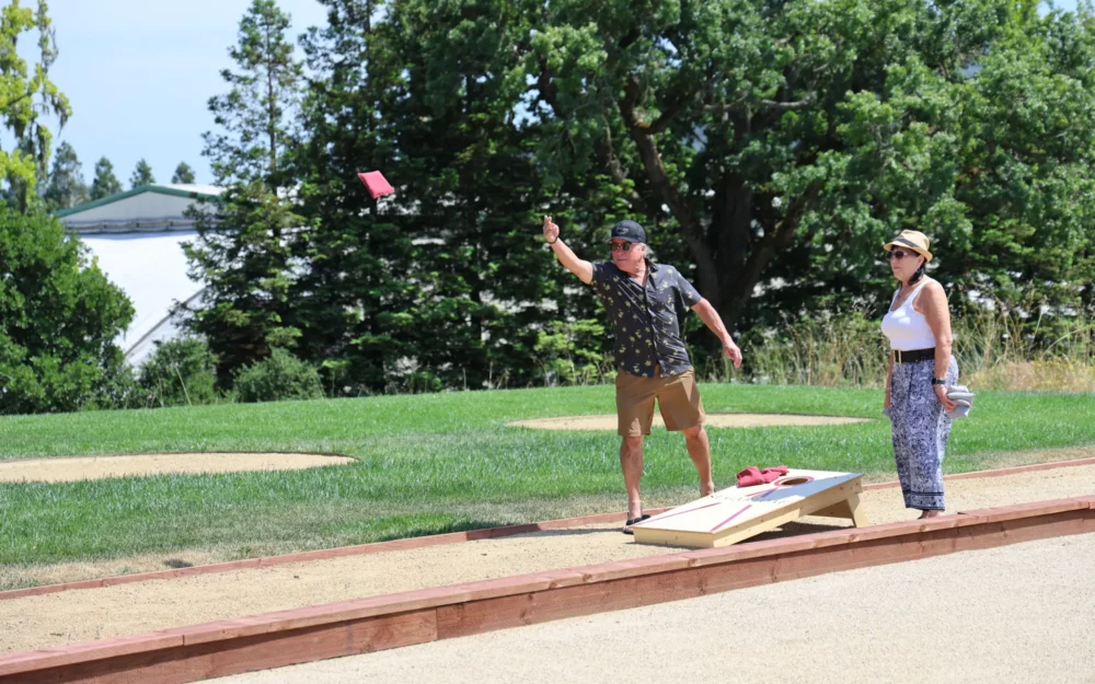 Man and woman playing corn hole at Sugarloaf Wine Co., game areas, outdoor event venue, Santa Rosa, CA